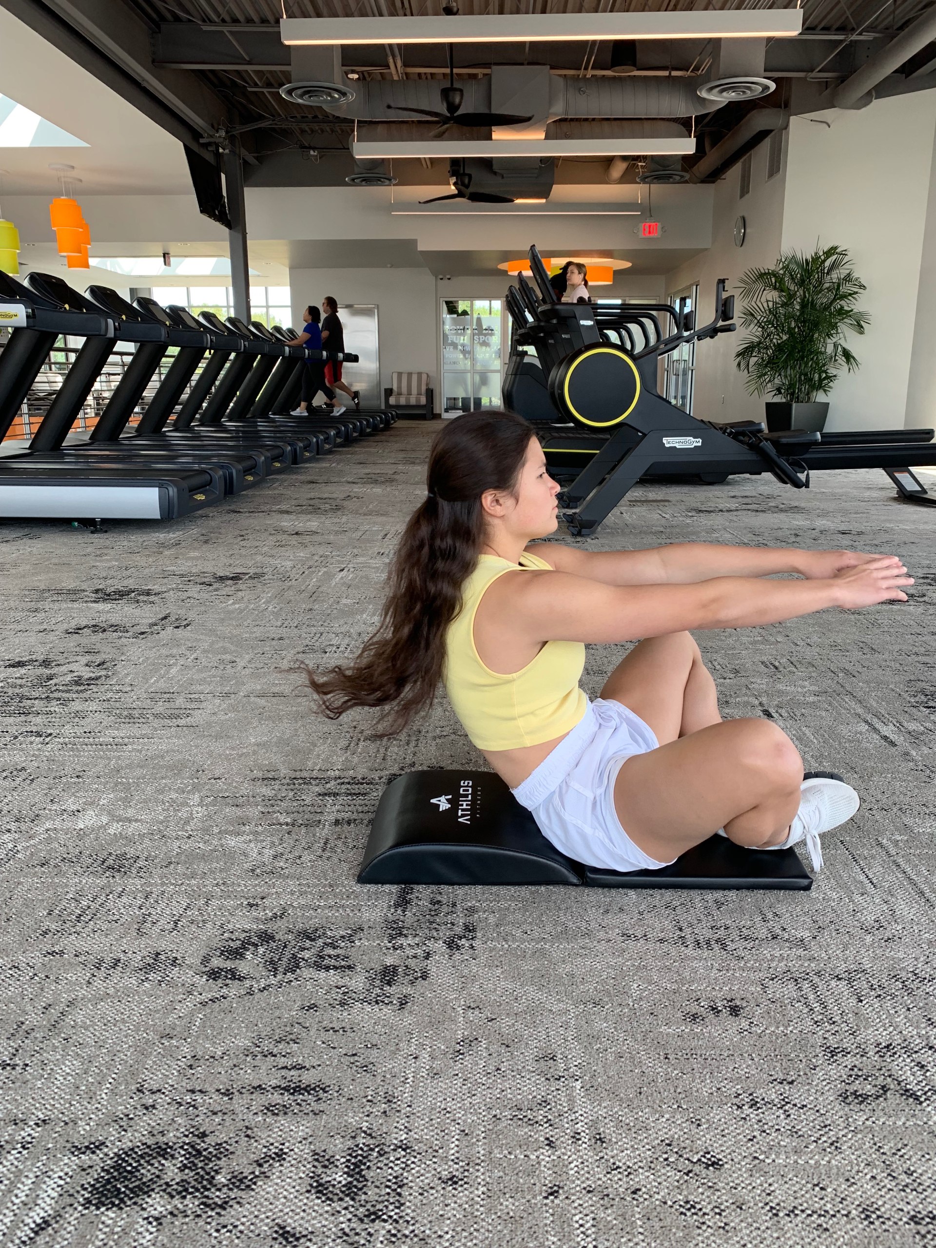 Woman performing sit-ups on Athlos Fitness ab mat with tailbone protector pad